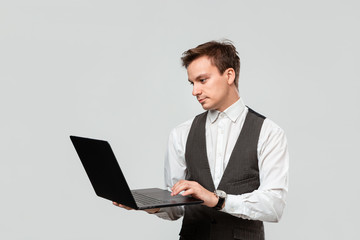 Confident manager holding laptop isolated over grey background