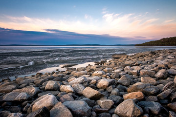 Fototapeta na wymiar Stones on the White Sea coast at sunset. Frozen water, summer, white nights.