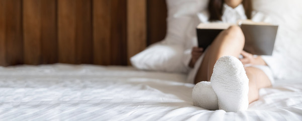 Asian woman reading a book on the bed after get up in morning with soft morning light. Morning...