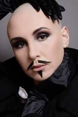 Fototapeta na wymiar Vintage style portrait of skinhead woman with smoky eye makeup and fake mustache on her face