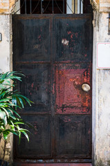 A old rusy black metal door found in a back side alley in Hanoi, Vietnam