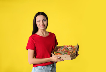 Beautiful woman with tasty pizza on yellow background