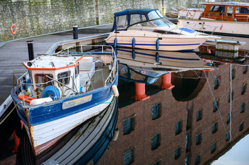 Close up of moored boats and buildings reflected in the still water of the Albert Dock, Liverpool