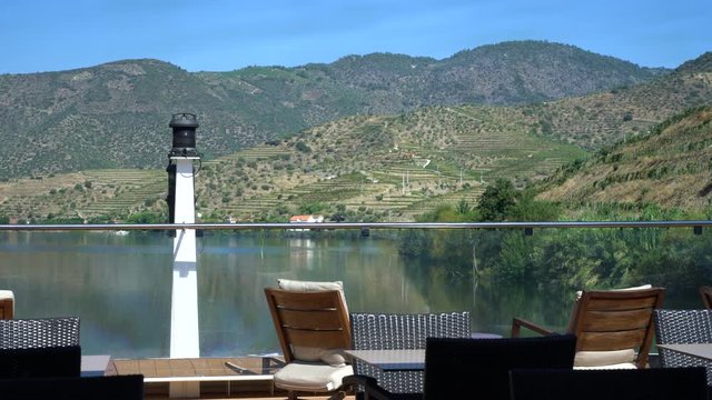 View downstream from a river cruise boat on the Douro in Portugal as the boat approaches vineyards and the front of the ship is shown in the frame