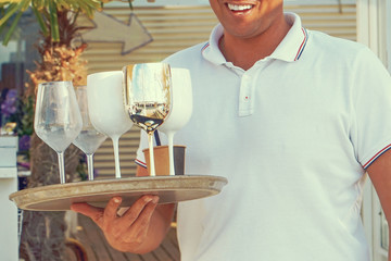 Hand of waiter is holding a tray with dirty dishes and empty glasses. Waiter cleaning the table in a restaurant. The concept of service.