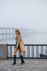 A long-haired attractive blonde walks along the autumn promenade in the morning. Fog. Blonde in a...