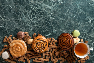 cinnamon bun, cookie, walnut, rye crackers, macarons view from above on marble