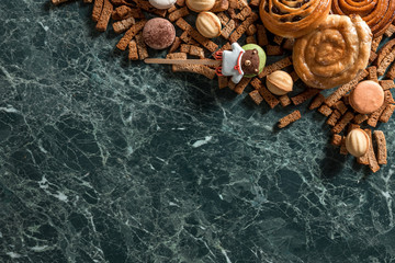 cinnamon bun, cookie, walnut, rye crackers, macarons view from above on marble