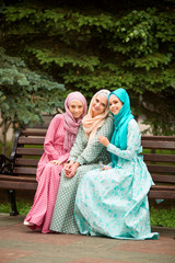Fototapeta premium three beautiful young women in muslim dresses in summer at the park