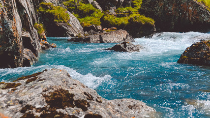 Turquoise water in river with stone shore. Sea tide, seething blue water in mountain stream