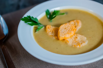 Cream of vegetable soup in a white bowl and spoon on a gray background. Close-up.
