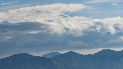 Hills in blue haze on horizon. Silhouettes of mountains in valley at sunset