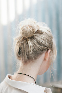 Close-up rear view of a young blonde haired woman with a hair bun