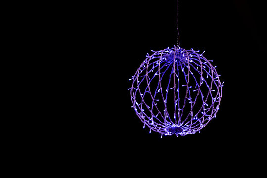 Blue purple glowing ball from garland on  black background. Isolate. Copy space. Front bottom view.