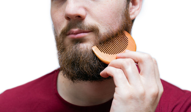 young man portrait with comb his beard and moustache on white isolated background