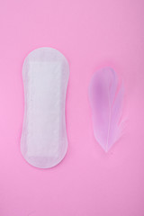 Menstrual pad with feathers on color background
