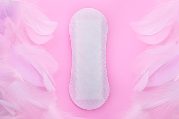 Menstrual pad with feather on color background