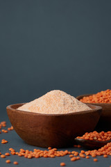 Red lentil flour in wooden bowl on gray background. Plenty of copy space