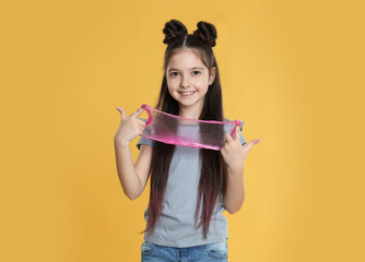 Little girl with slime on yellow background