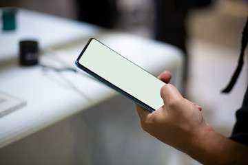 man holds new smartphone with white screen copyspace. close up, soft focus. background in blur