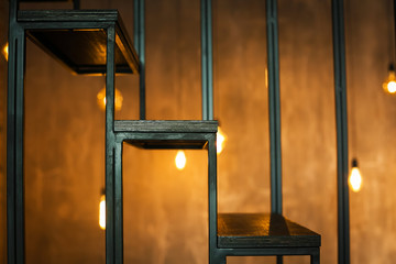  Steps of wooden and metal stairs on the background of a loft wall and burning lamps