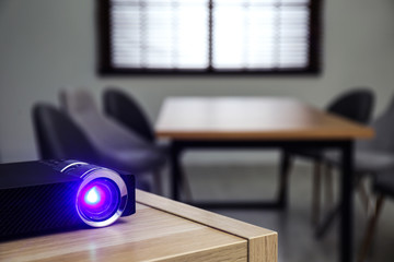 Modern video projector on wooden table in conference room. Space for text
