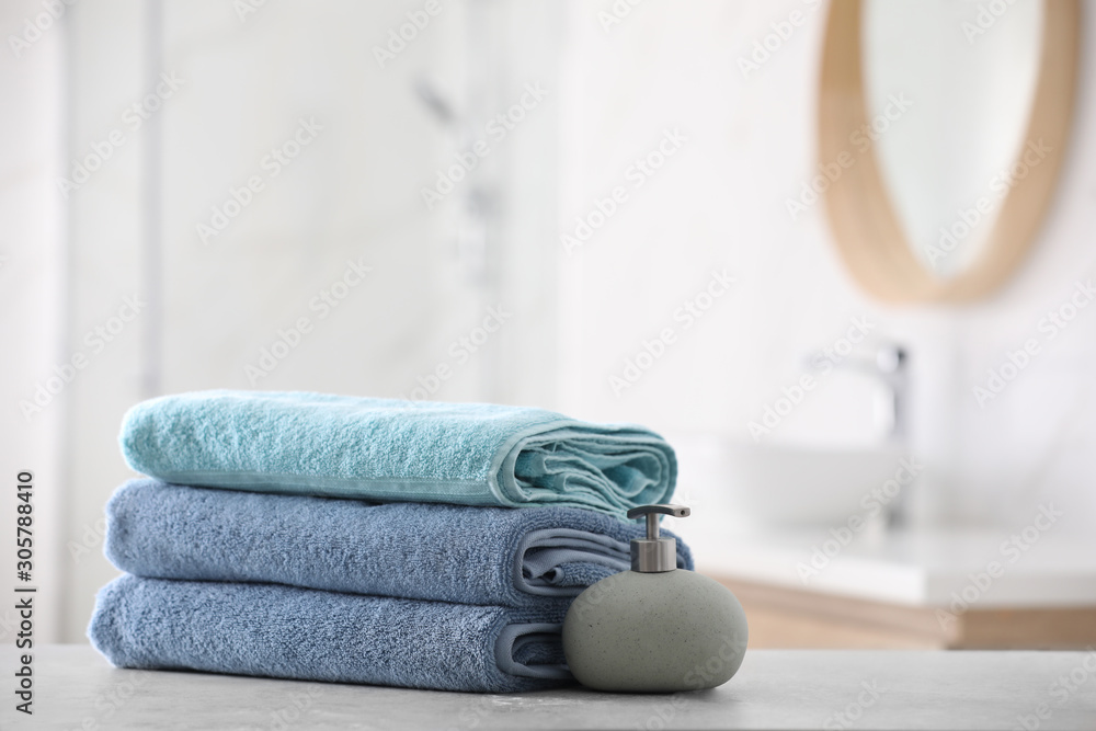 Wall mural stack of fresh towels and soap dispenser on table in bathroom