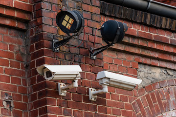 Two surveillance cameras on a red brick wall, with infrared spotlights