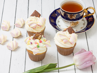 Three cupcakes filled with air cream and decorated with chocolate with nuts and candy in the form of Valentines.