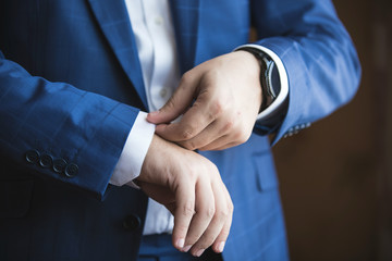 Obraz premium A man in an elegant suit adjusts his shirt sleeve.