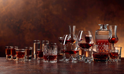 Set of strong alcoholic beverages in glasses on a brown background.