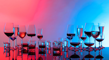 Set of various alcoholic beverages in glasses on a black reflective background.