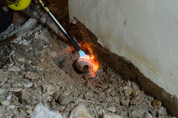 professional plumber warms the stuck pipe