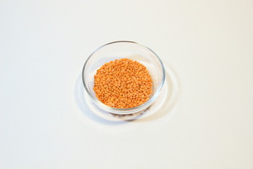 Glass bowl with pile of red lentils isolated on white background