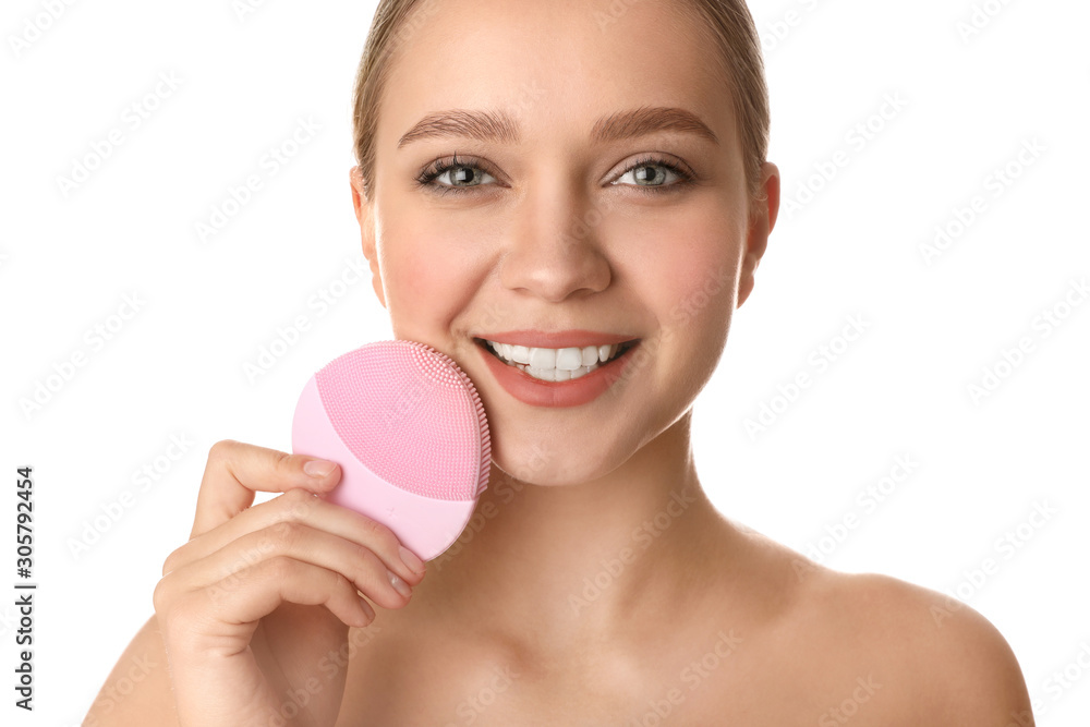 Poster Young woman washing face with cleansing brush on white background. Cosmetic product