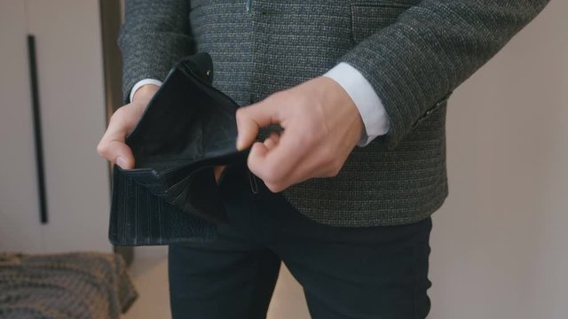 Close up of businessman's hands showing empty lether wallet with no money. Concept of personal or business bankruptcy, financial crisis, loans and debts, shortage of funds.