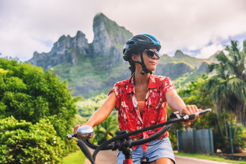 Bicycle tourism woman tourist biking on E-bike rental in Bora Bora, island, Tahiti, French Polynesia. Active sport travel on summer vacations. Adventure fun cyclist on bike. - obrazy, fototapety, plakaty