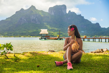 Bora Bora tourist woman relaxing on beach drinking fresh coconut water by Otemanu mount in landscape. French Polynesia travel vacation. - obrazy, fototapety, plakaty