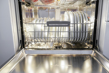 Dishwasher with dishes in kitchen furniture.