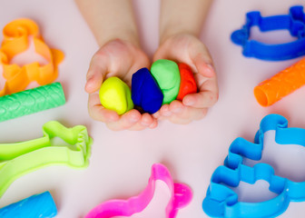 Child hands playing with colorful clay. Homemade plastiline. Plasticine. play dough. Girl molding modeling clay. Homemade clay.