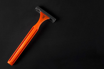 New disposable razor blade on a black background. Close-up, top view. Skin care concept.