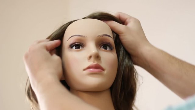 Man puts a wig on a female mannequin