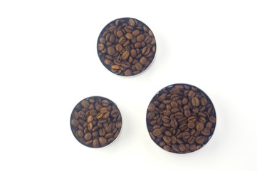 Fototapeta na wymiar three containers of different sizes of round shape filled with coffee beans and standing in a row next to each other on a white background