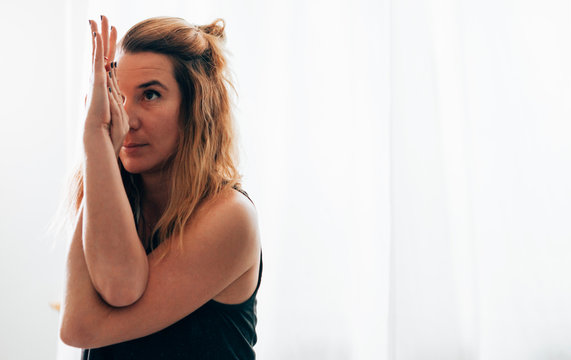 portrait of a young caucasian woman doing the yoga position of the eagle with crossed hands - balance and focus exercise