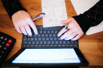 middle aged business woman is working at home. Late at night she is doing overtime with her tablet computer and writing 'to do' notes 