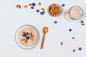 Fototapeta na wymiar Bowl of oatmeal flakes, almonds and fresh blueberries