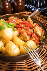 Fried pieces of chicken with red peppers and onions.