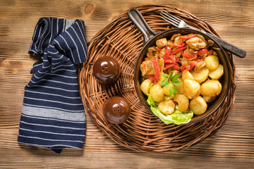Fried pieces of chicken with red peppers and onions.