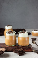 Chocolate mousse with whipped cream and pieces of chocolate in portion glasses, light grey background. Copy space.