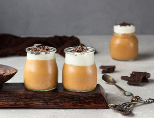 Chocolate mousse with whipped cream and pieces of chocolate in portion glasses, light grey...